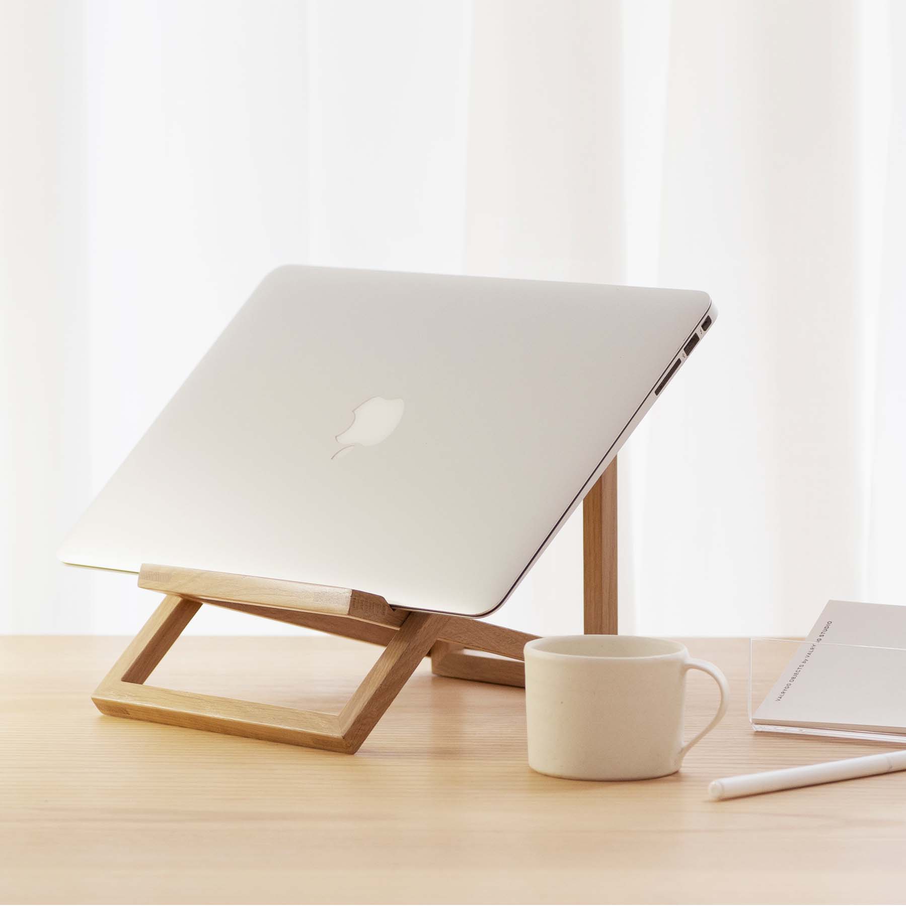 Foldable laptop stand in solid oak holding a computer